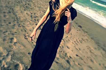 North Carolina fashion and lifestyle blogger Jessica Linn wearing a navy blue maxi dress, silver sandals, an da feather pendant necklace on a beach in Florida.