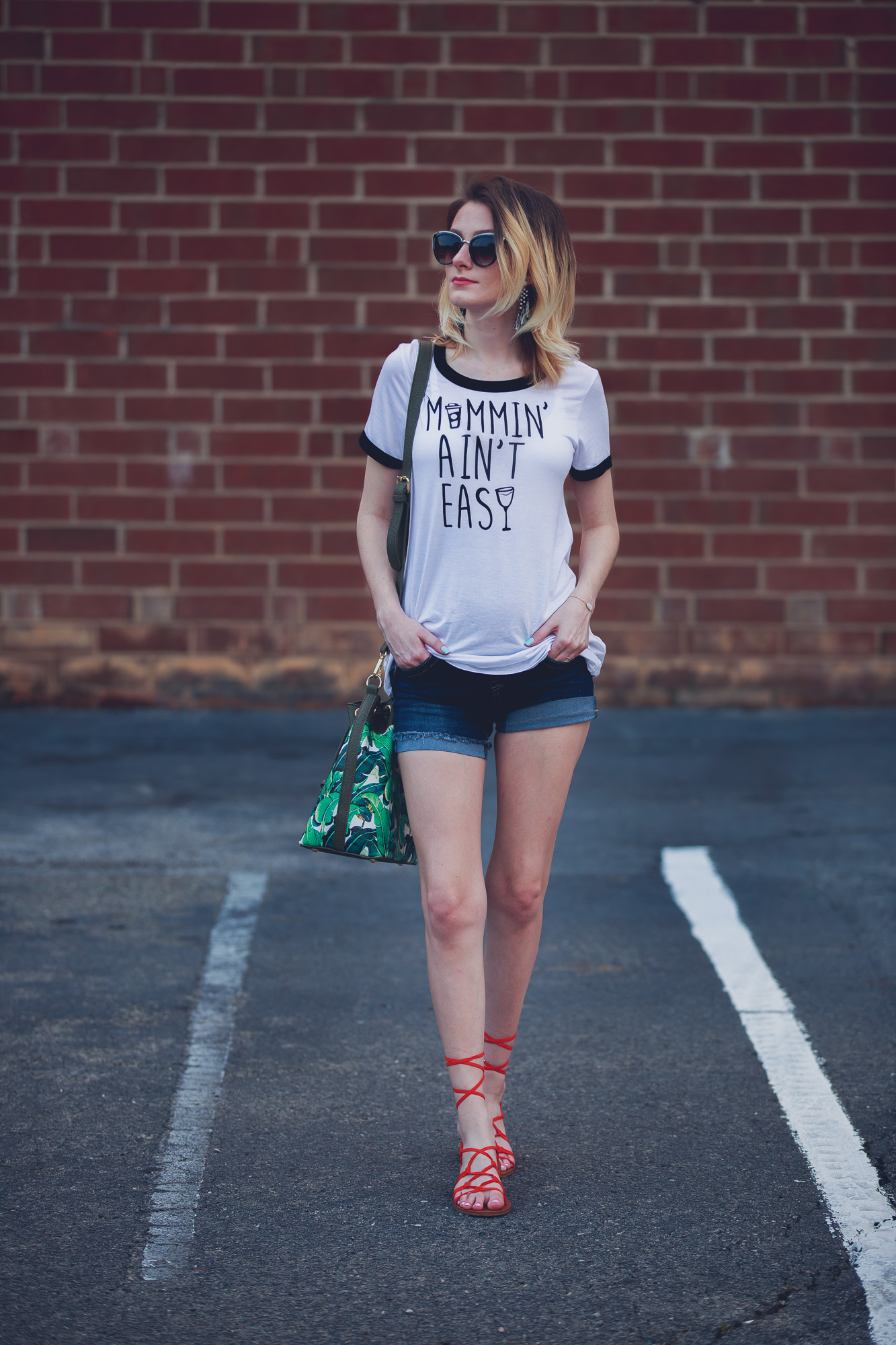 Lifestyle and fashion blogger Jessica Linn from Linn Style wearing maternity shorts from Ross, sandals from Forever21, a tee shirt from Charming Charlie's, earrings from Sugarfix by Baublebar from Target, and sunglasses and a palm tree purse from Charming Charlie's 