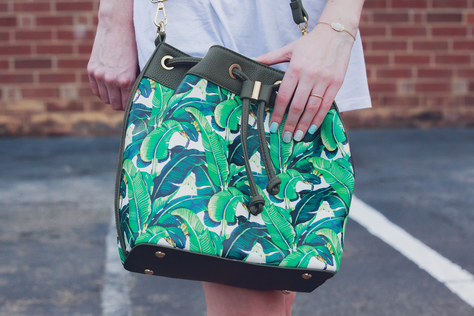 Lifestyle and fashion blogger Jessica Linn from Linn Style wearing maternity shorts from Ross, sandals from Forever21, a tee shirt from Charming Charlie's, earrings from Sugarfix by Baublebar from Target, and sunglasses and a palm tree purse from Charming Charlie's 