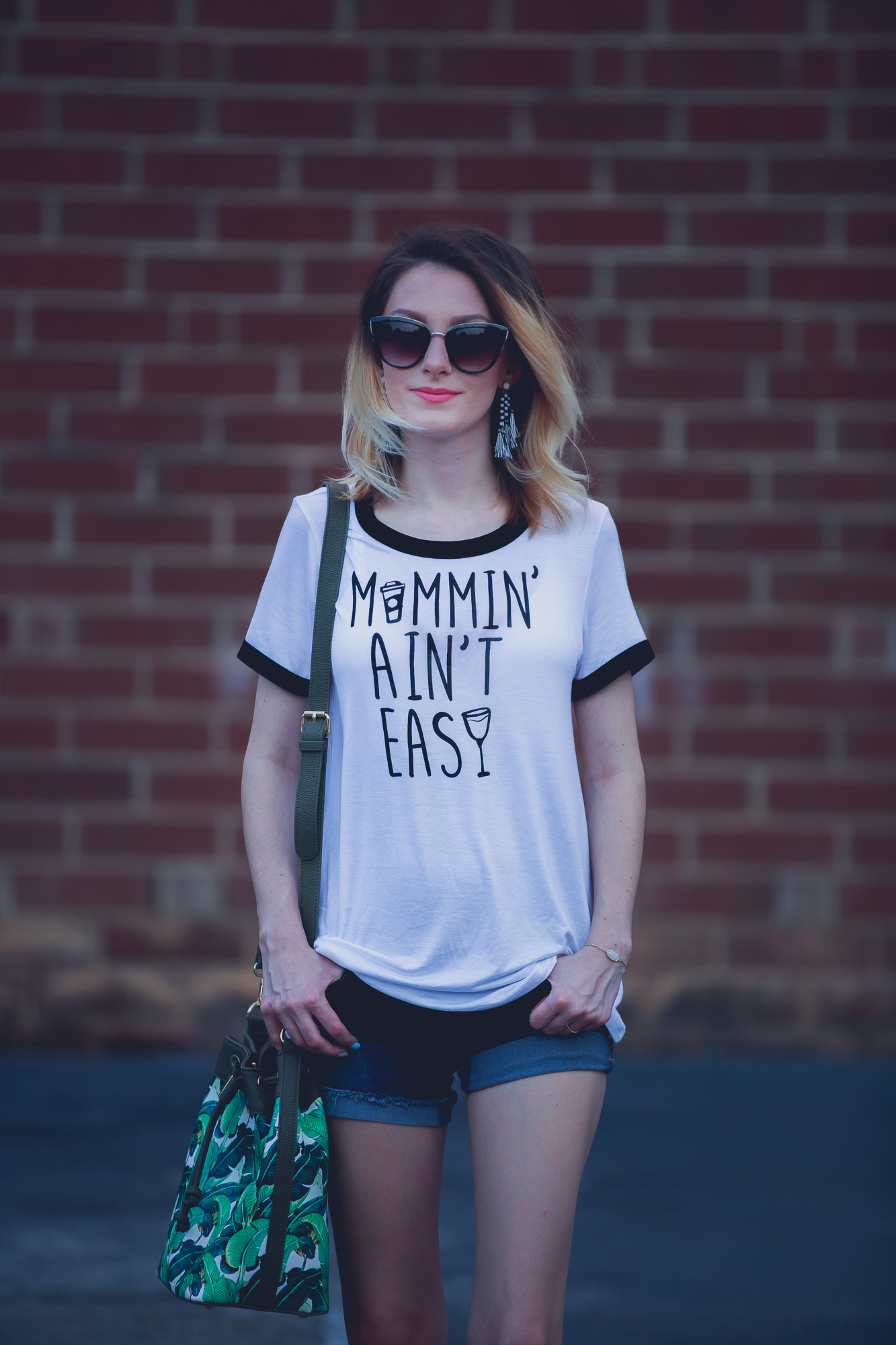 Lifestyle and fashion blogger Jessica Linn from Linn Style wearing maternity shorts from Ross, sandals from Forever21, a tee shirt from Charming Charlie's, earrings from Sugarfix by Baublebar from Target, and sunglasses and a palm tree purse from Charming Charlie's 