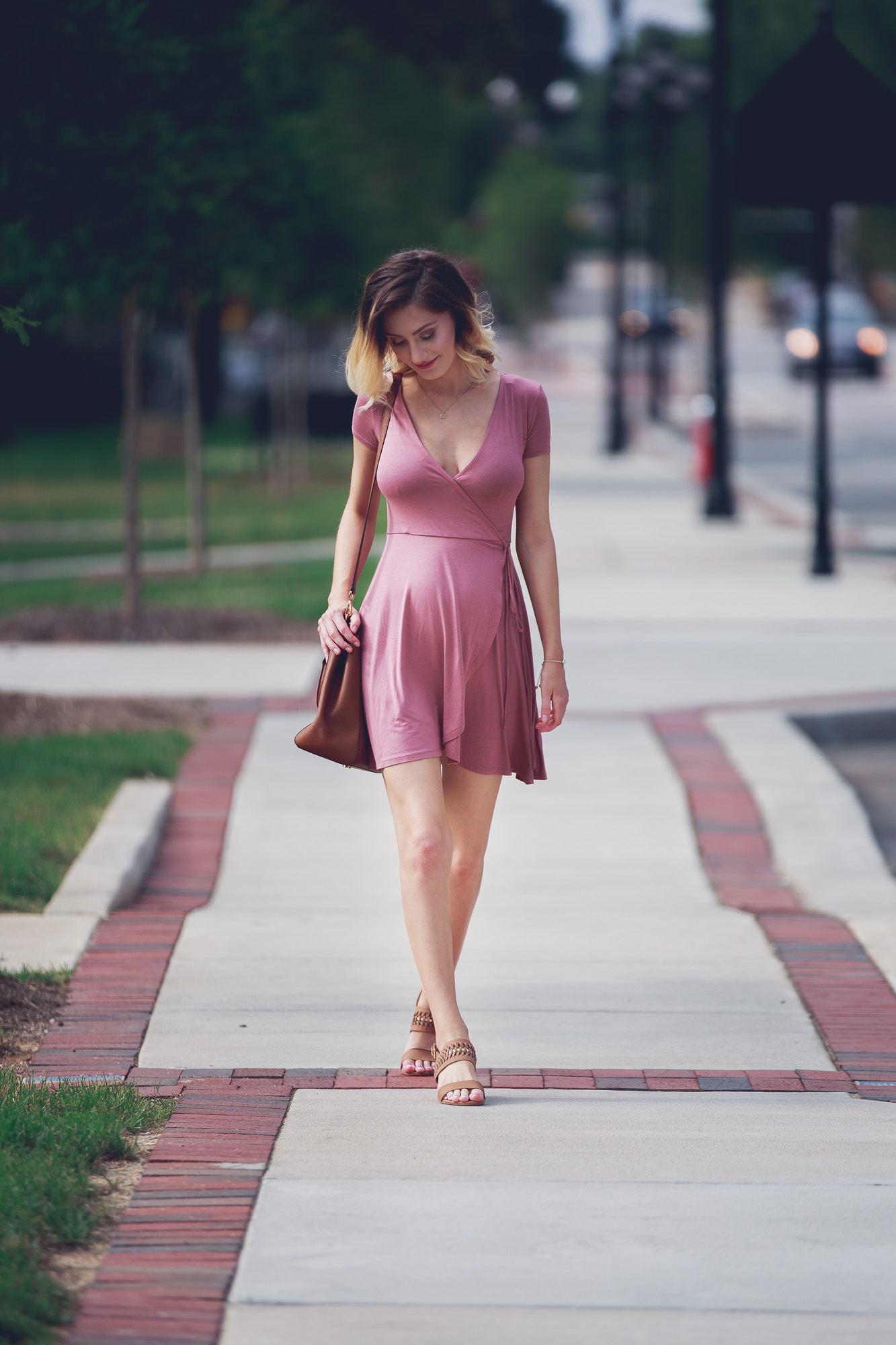 Lifestyle and Fashion blog Linn Style bye Jessica Linn Outfit of the Day post and summer outfit inspiration wearing a mauve Forever21 wrap dress (great for pregnancy) a Dogearred jewelry lotus necklace, a Kendra Scott bracelet, World Market earrings, brown low sandal heels from Ross, and carrying a Michael Kors tan purse while walking in Historic Downtown Cary North Carolina.