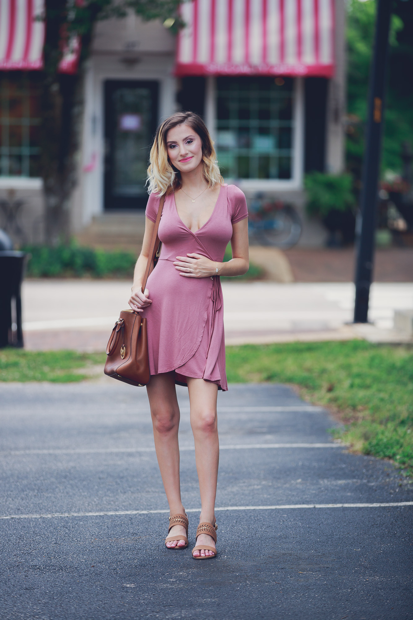 Lifestyle and Fashion blog Linn Style bye Jessica Linn Outfit of the Day post and summer outfit inspiration wearing a mauve Forever21 wrap dress (great for pregnancy) a Dogearred jewelry lotus necklace, a Kendra Scott bracelet, World Market earrings, brown low sandal heels from Ross, and carrying a Michael Kors tan purse while walking in Historic Downtown Cary North Carolina.
