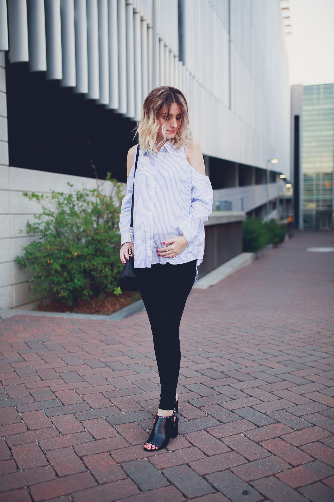 Fashion Blogger and lifestyle blogger Jessica Linn from Linn Style wearing a cold shoulder pinstripe button up blouse from Forever21, black leggings from Romwe, and black silver studded heels from Charming Charlie's also carrying a black and gold Michael Kors Purse. Photos taken in Downtown Raleigh North Carolina.
