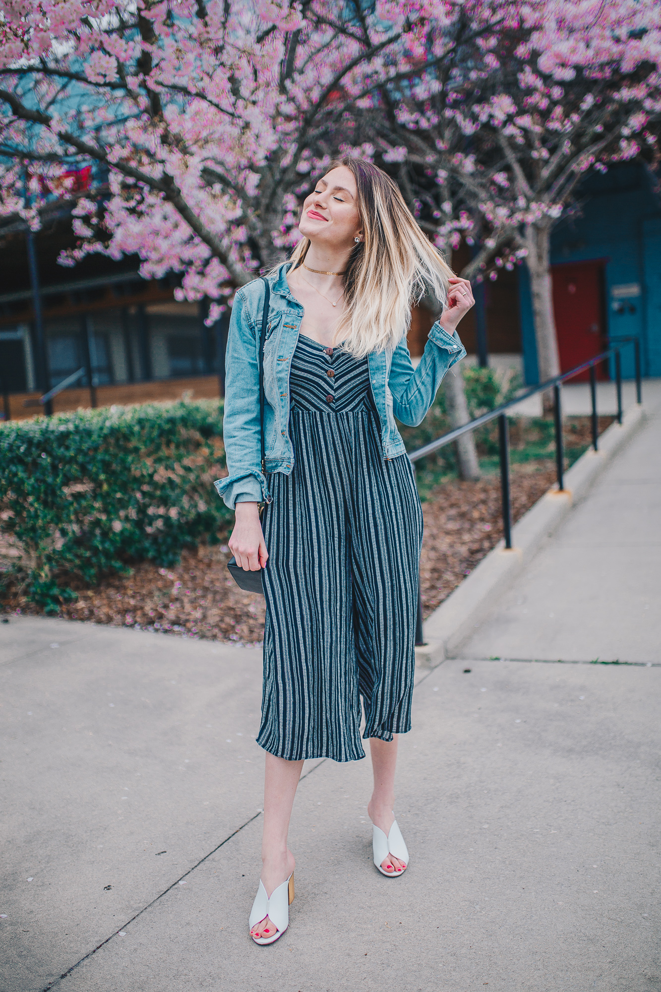 How To Style A Jumpsuit by North Carolina fashion and lifestyle blogger Jessica Linn. Navy blue chevron culotte jumpsuit from Forever21 worn with a denim jacket, white heeled mules from Target Who What Wear, a black Michael Kors Purse from Macy's, a gold chevron choker form Cary NC jewelry store CY Design Studio, and necklace from Copper Bloom. A casual and effortless summer outfit.