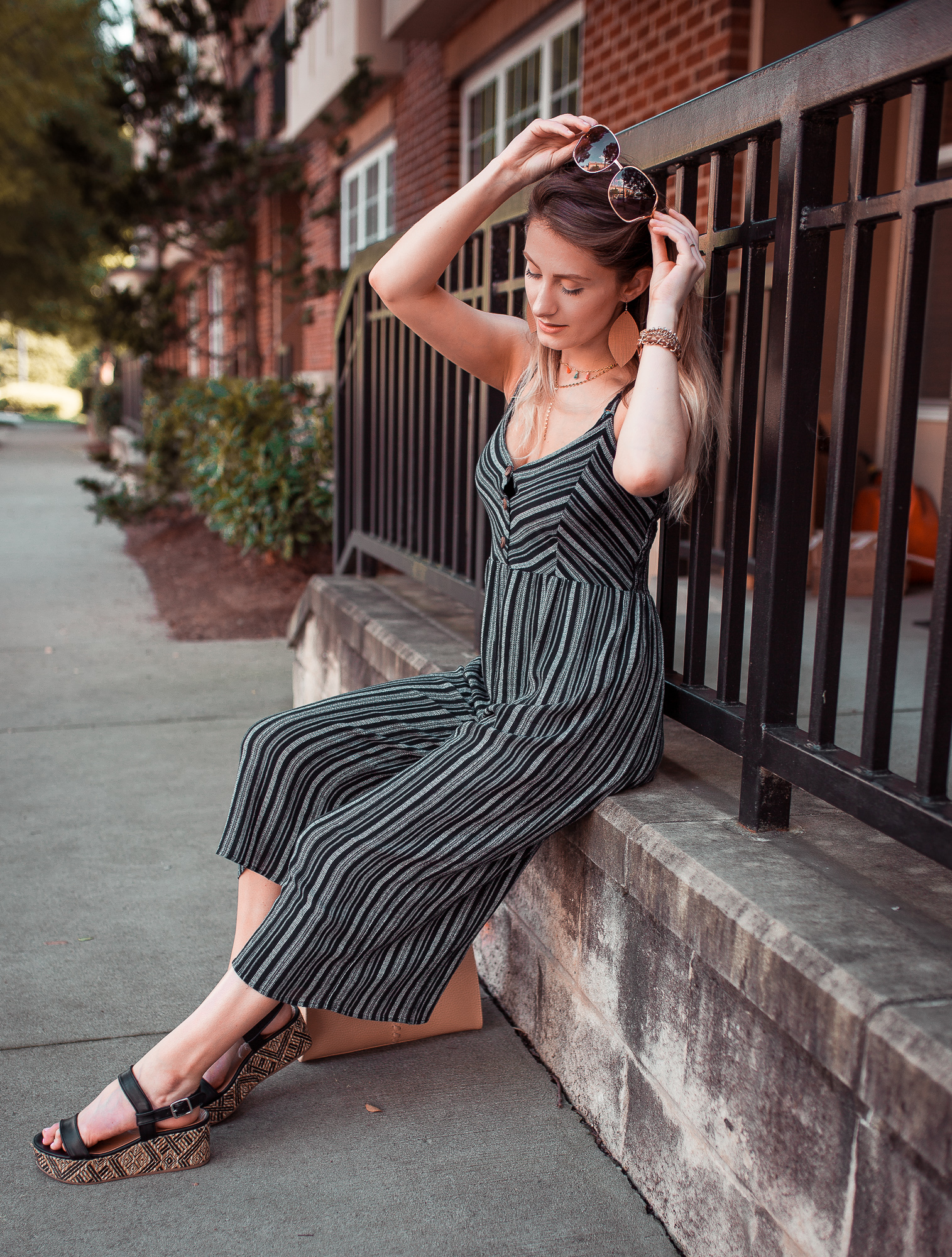 North Carolina fashion and lifestyle blogger Jessica Linn styling a navy striped jumpsuit from Forever21, platform sandals from Target, a layered tassel chocker from bauble bar, and vegan leather earrings from RSA Studios.
