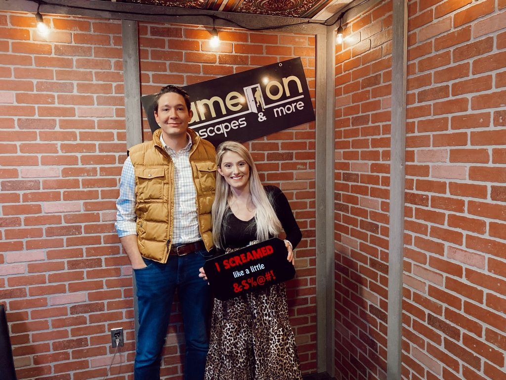 How To Wear A Non-Maternity Maxi Skirt While Pregnant by Jessica Linn.  Pregnant North Carolina fashion blogger Jessica Linn wearing a long leopard print skirt, black long sleeve shirt, and wenda cut-out booties at Game on Escape Rooms. With husband Joel Pagán.