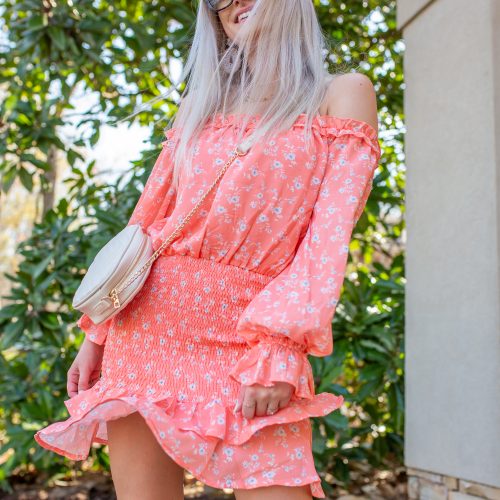 Coral mini off the shoulder ruched mini dress with white and blue floral print. White braided heels, white purse. Spring outfit
